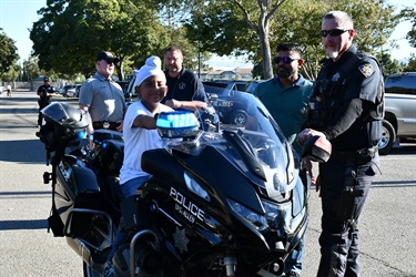 Tracy Police motorcycle officers posing with community members beside police motorcycles.