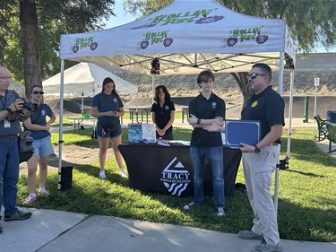 Tracy Police officers and community members gathered at an outdoor outreach booth in a park.