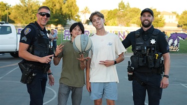 Two Tracy Police officers posing with community members at an outdoor event