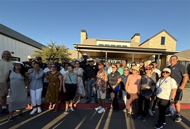 Tracy Police officers and community members posing for a large group photo outside a building.