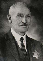 Historic black-and-white portrait of a Tracy police chief wearing a suit with a star-shaped badge.