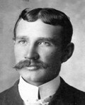 Historic black-and-white portrait of a Tracy police chief with a mustache, wearing a suit and tie.